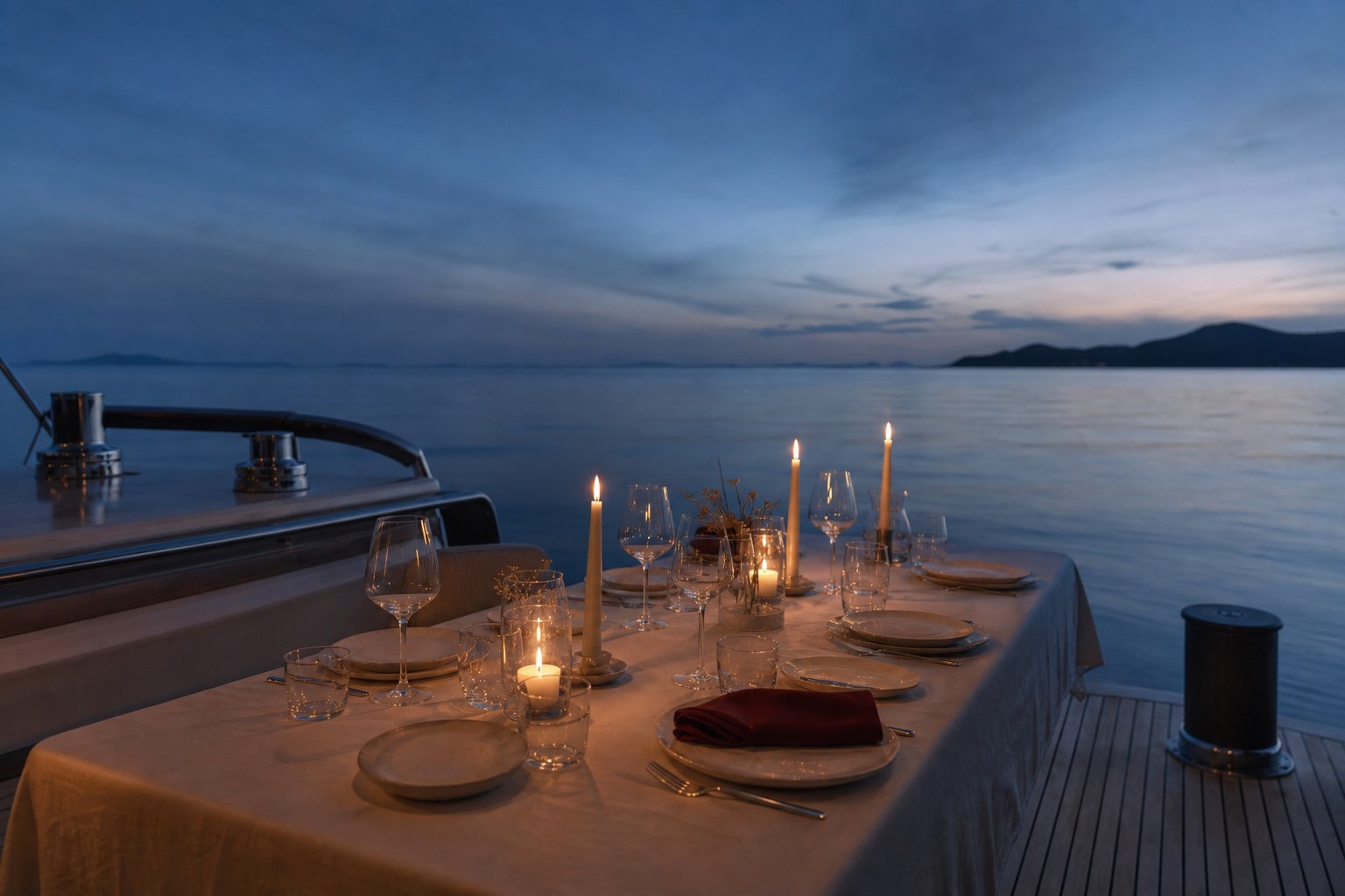 Candlelit private dining table aboard a yacht at blue hour